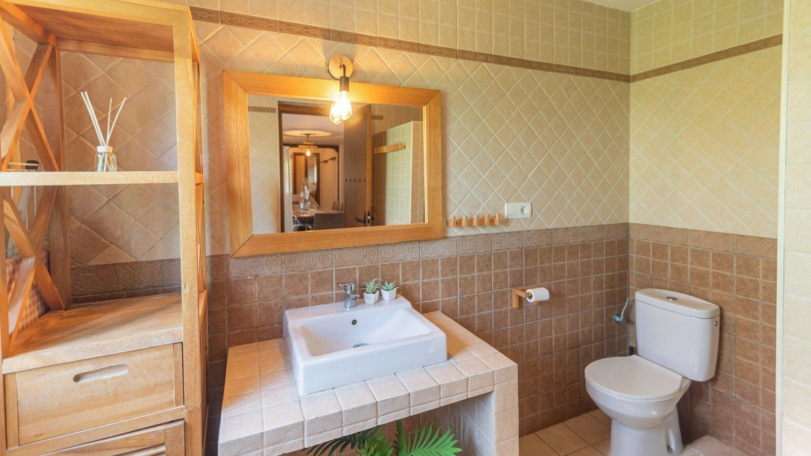 Une salle de bain avec un meuble-lavabo en bois, un lavabo blanc, un miroir et des toilettes.