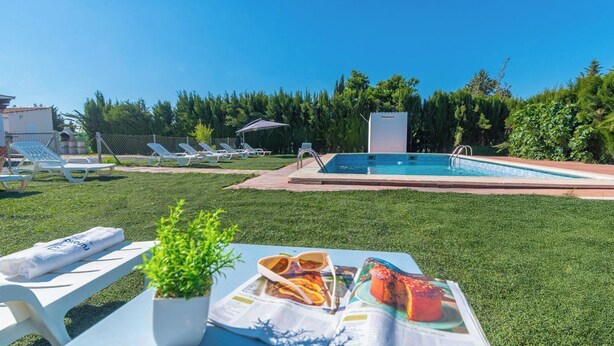 Un espace aménagé au bord de la piscine, avec des chaises longues, une table où sont servis des plats et des boissons, et la piscine elle-même.