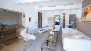 Ein großzügiger Wohnbereich mit Steincheminée, weißen Sofas und einem Holztisch.