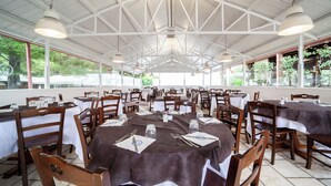 Un restaurant spacieux avec de hauts plafonds et de grandes fenêtres, où les tables et les chaises sont disposées avec soin.