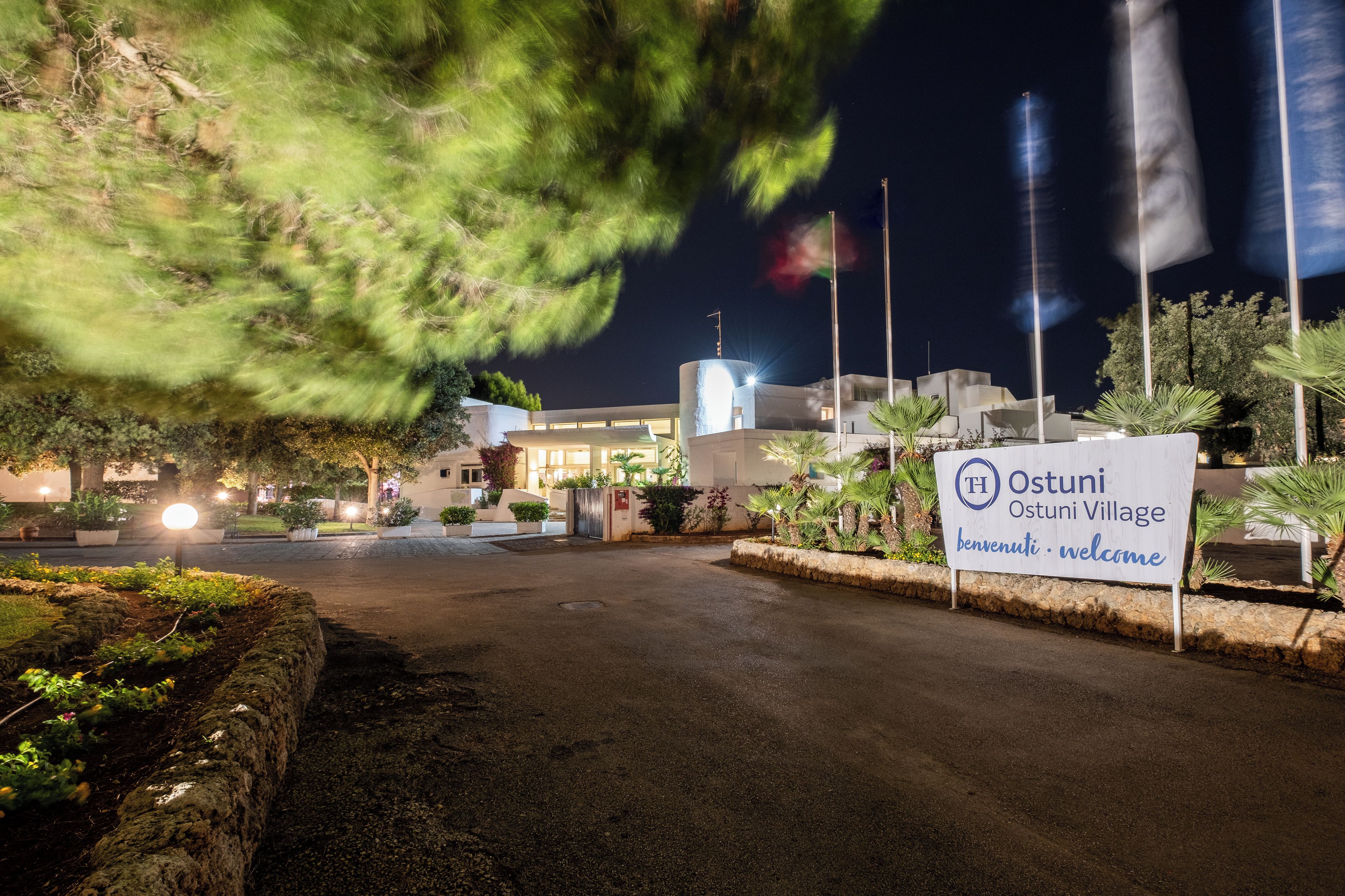 A sign for Ostuni Village with a welcoming message.