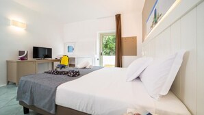 Une chambre d’hôtel avec un lit, un bureau avec un ordinateur, une télévision et une fenêtre avec des rideaux.