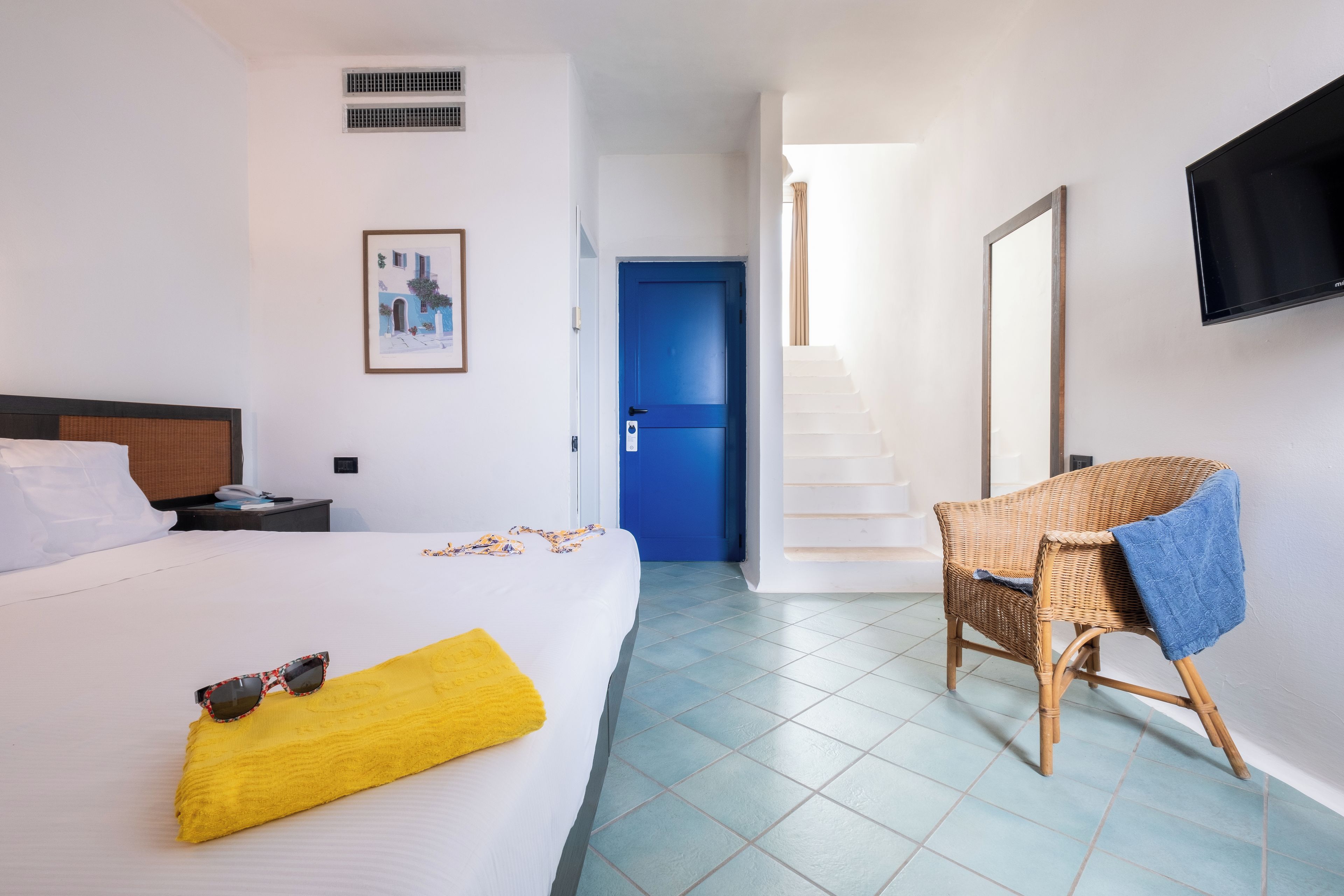 A hotel room with a bed, a chair, a TV, and a staircase.