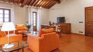 Un salón espacioso con sofás naranja, una mesa de centro de vidrio y un techo de madera.