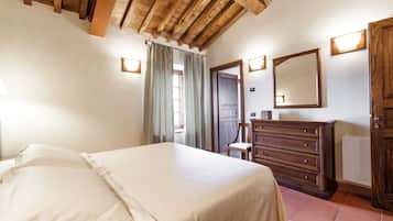 Une chambre à coucher avec un lit, une commode en bois et un miroir au mur.