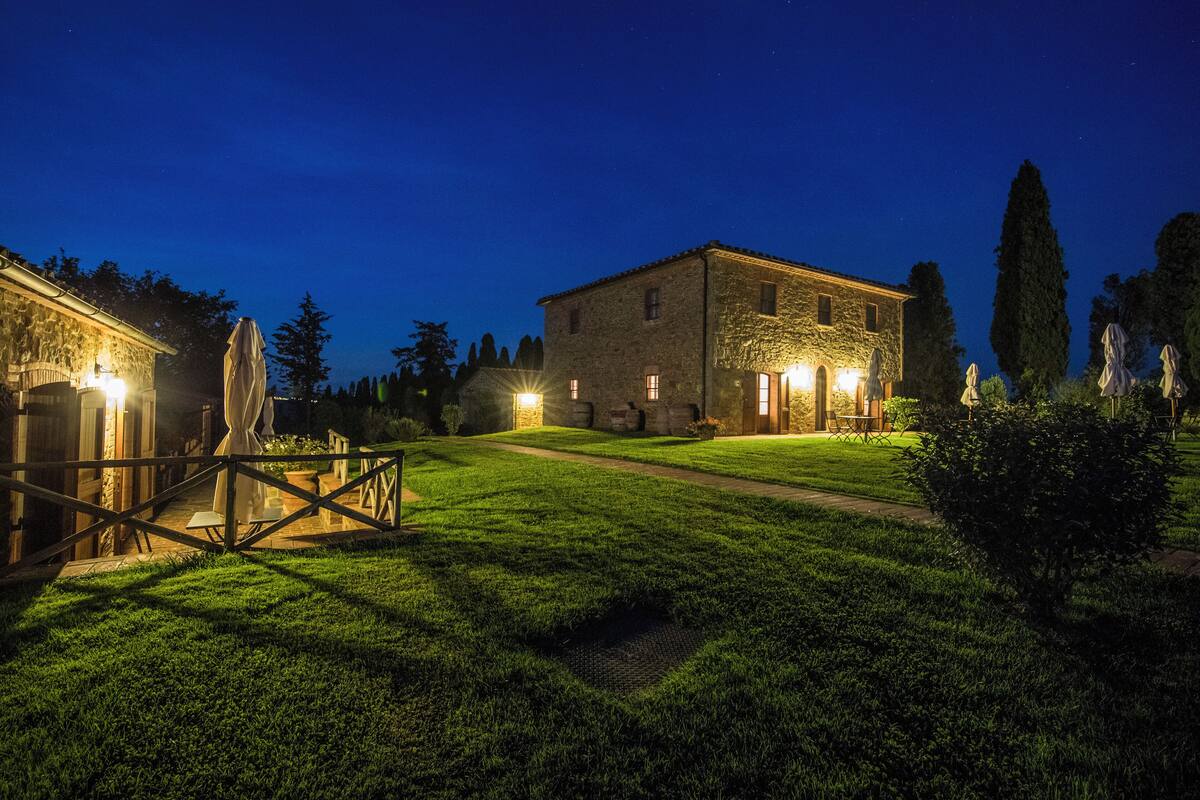 A stone building with a well-lit entrance and a grassy lawn.