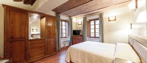 Un dormitorio con una cama grande, un armario de madera y una televisión.