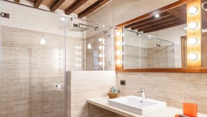 A bathroom with a large mirror, vanity, sink, and shower. - Tenuta Montecucco (Cinigiano)