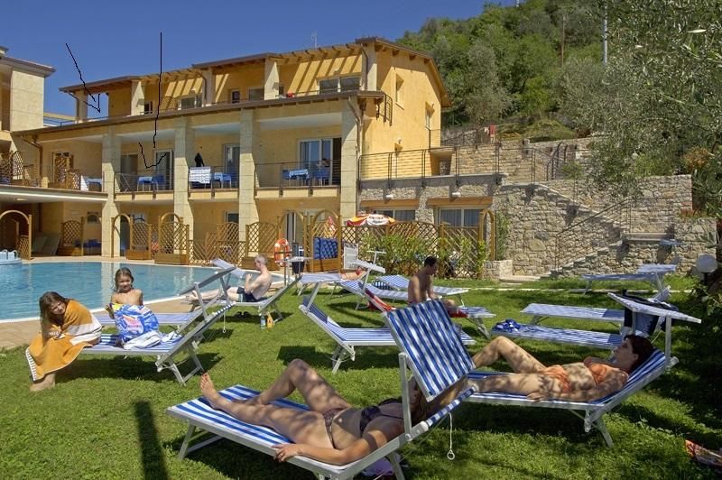 A poolside area with lounge chairs and a building with multiple balconies.