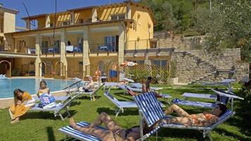 A poolside area with lounge chairs and a building with multiple balconies.