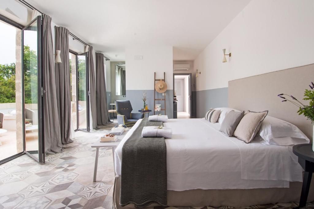 Quarto de hotel com uma cama grande, uma escrivaninha e vista pelas portas de vidro.