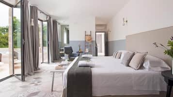 Quarto de hotel com uma cama grande, uma escrivaninha e vista pelas portas de vidro.