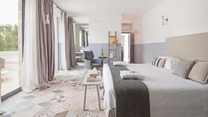 A hotel room with a bed, a chair, a table, and a view of the outdoors. - Masseria San Giovanni (Fasano)