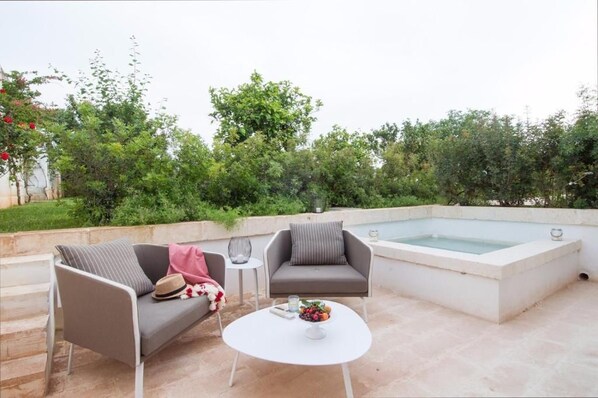 An outdoor seating area with two sofas, a small table, and a hot tub. - Masseria San Giovanni (Fasano)