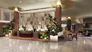 Un vestíbul modern amb una recepció, plantes en testos i una zona de seients amb cadires.