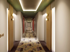 A hotel hallway with a patterned carpet, wooden paneling, and wall-mounted light fixtures. - Hyatt Regency Rome Central (Rome)