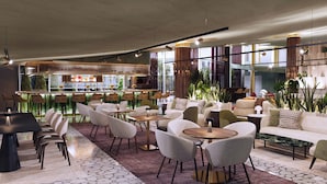 A modern lounge area with seating, a bar, and large windows offering views. - Hyatt Regency Rome Central (Rome)