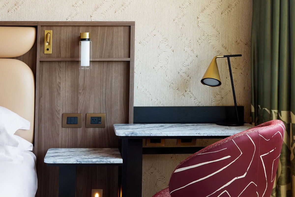 Une chambre d’hôtel avec un lit, un bureau doté d’une lampe et une chaise.