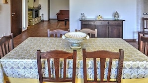 A dining area with a table set for four, a chandelier, and a view into the living room. - Etna Villa il Pino (Trecastagni)