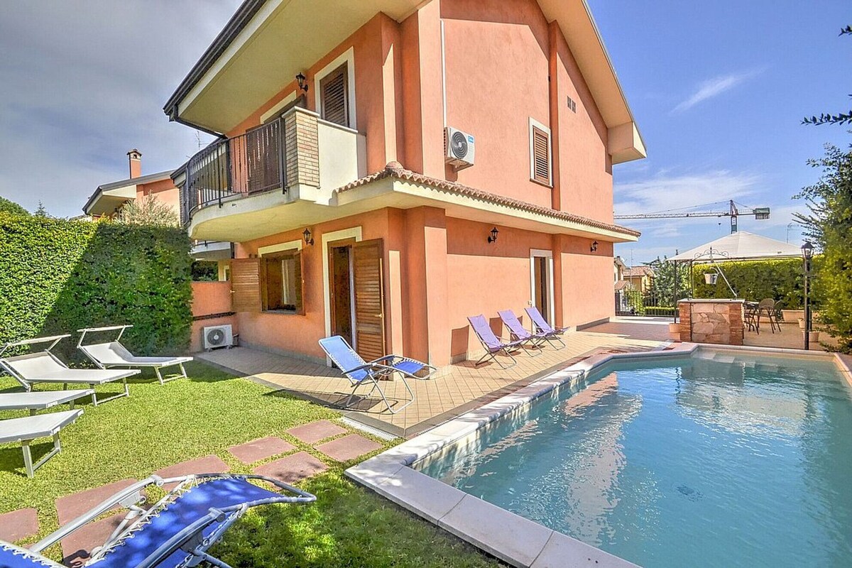 Ein zweistöckiges Haus mit Swimmingpool, Sitzgelegenheiten im Freien und einem gepflegten Garten.