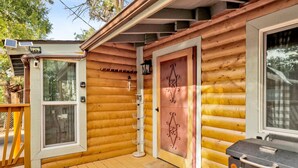 A wooden cabin with a deck, a door with decorative metalwork, and a barbecue grill. - Sugar Bear Chalet #2559 (Sugarloaf)