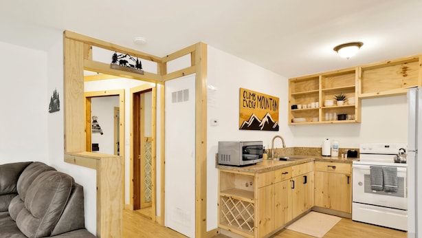 A compact kitchen with wooden cabinets, a built-in oven, and a microwave. - Sugar Bear Chalet #2559 (Sugarloaf)