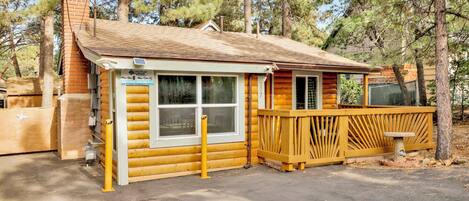 A log cabin with a fenced deck, a chimney, and a sign indicating no street parking.