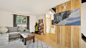 A modern living room with a grey sofa, a coffee table, and a wooden wall with a mounted deer head. - Sugar Bear Chalet #2559 (Sugarloaf)