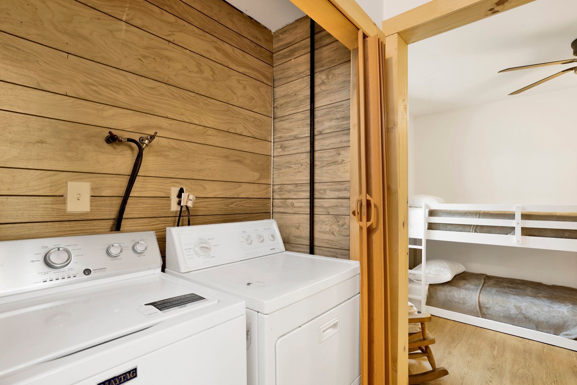 Un área de lavandería con dos lavadoras blancas y una pared de madera.