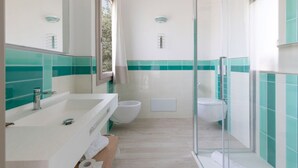 A modern bathroom with a glass shower enclosure, a white sink, and a toilet. - Eliantos Hotel and Spa (Pula)