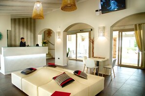 A hotel lobby with a reception desk, a seating area with cushions, and a dining table with chairs. - Eliantos Hotel and Spa (Pula)