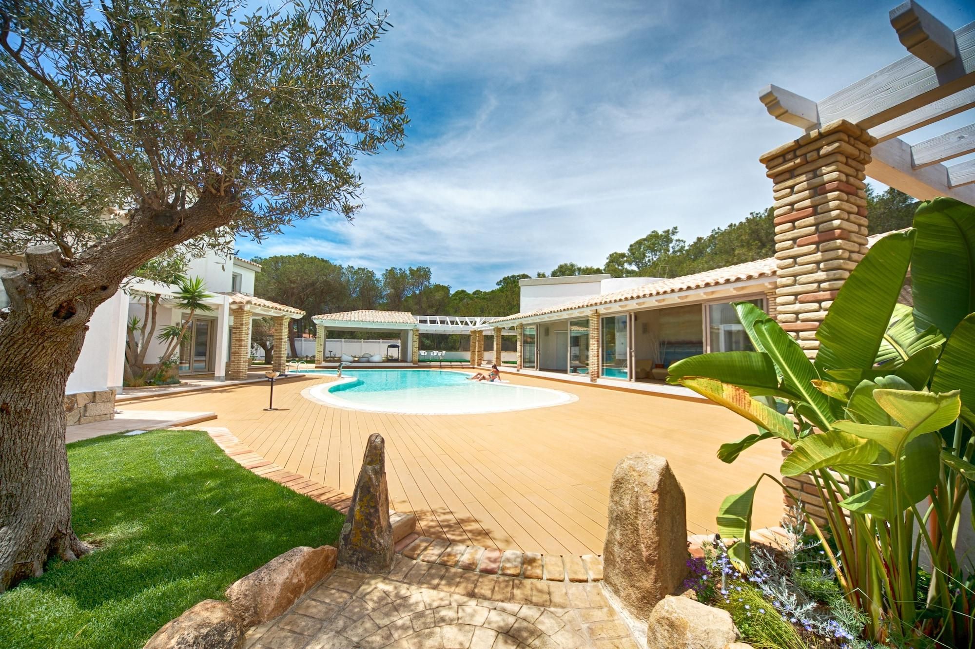 A pool area with a circular pool, a pergola, and a stone wall.