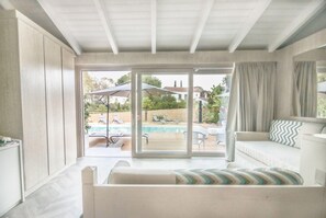 A modern living room with a large sliding glass door leading to an outdoor pool area. - Eliantos Hotel and Spa (Pula)