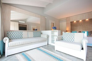 A modern living room with a white sofa set, a patterned rug, and a large mirror. - Eliantos Hotel and Spa (Pula)