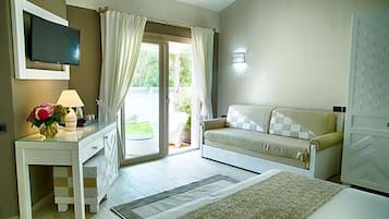 Un dormitorio con cama, sofá, televisor, escritorio y ventana con cortinas.