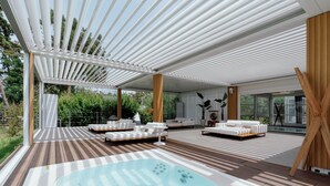 Un espace de détente extérieur moderne, doté d’un jacuzzi, d’une terrasse en bois et de canapés blancs.