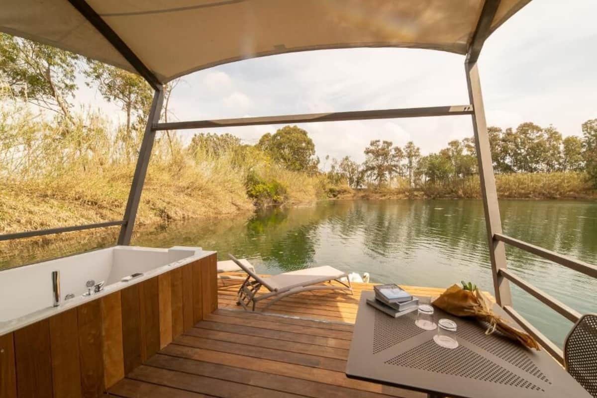 Eine Terrasse mit Badewanne, Liegestühlen und einem Tisch mit Gläsern und einem Blumenstrauß.