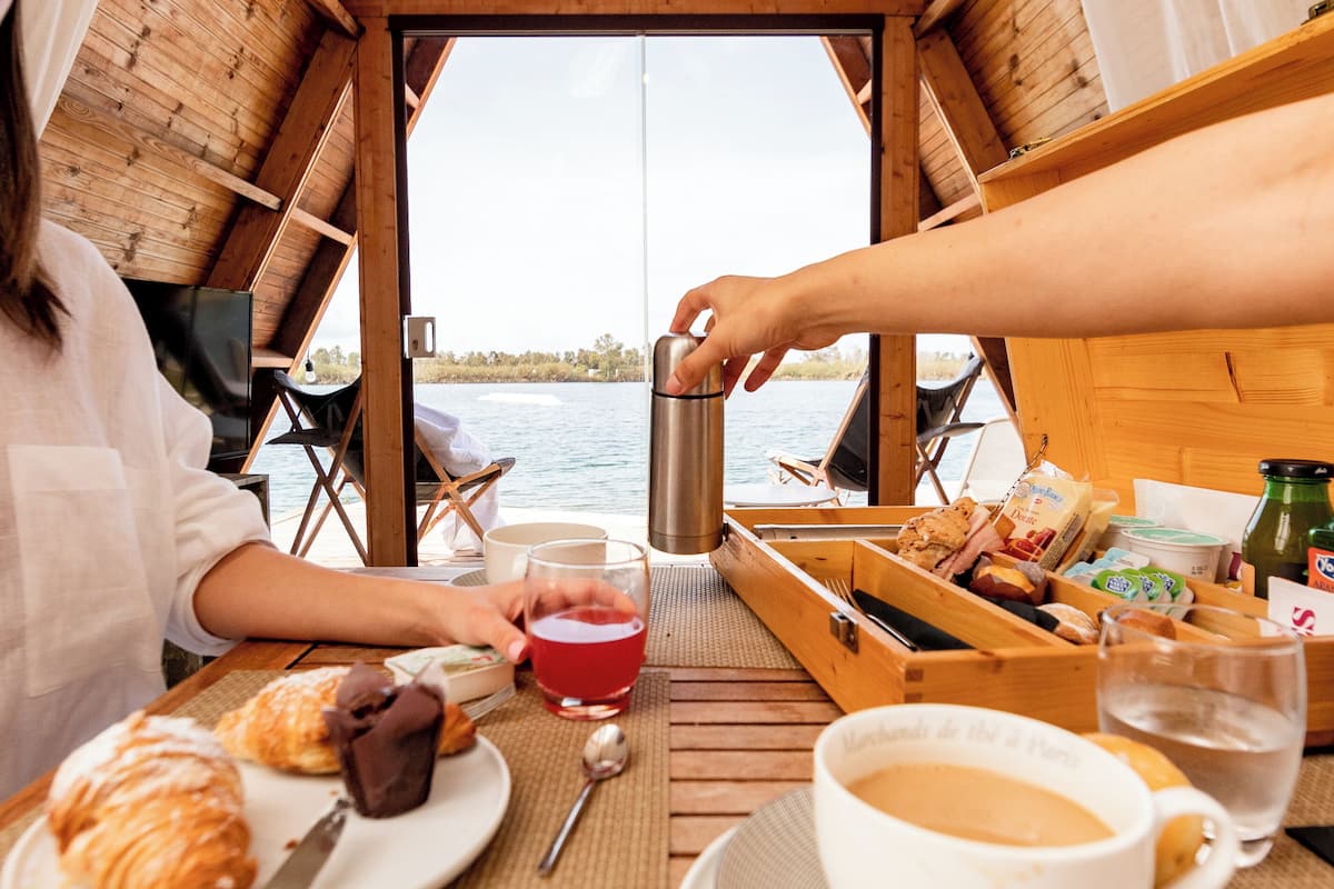 Een houten boot met een ontbijtstafel, compleet met croissants, koffie en een thermoskan.