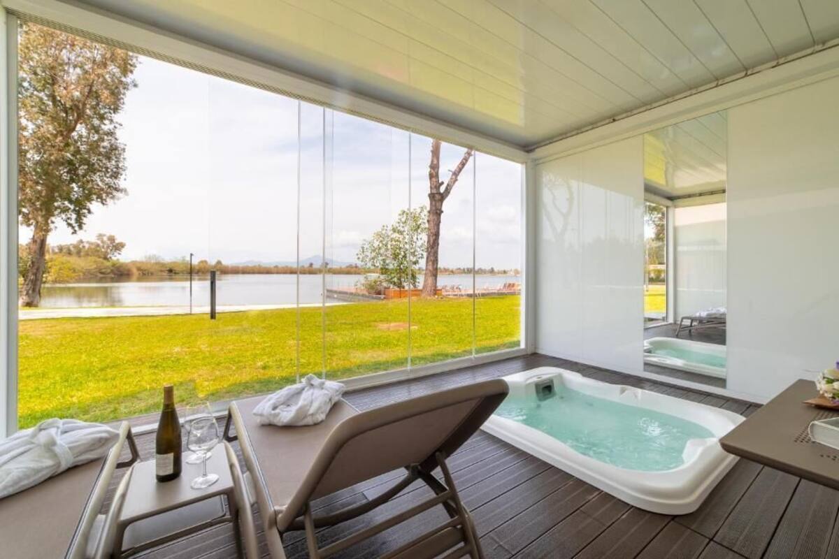 Een modern buitenzwembad met uitzicht op een meer en een grasrijk landschap.