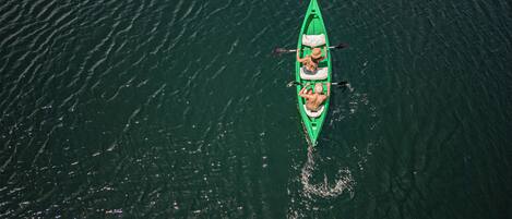 A green kayak with two paddlers on a calm body of water.