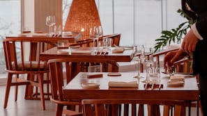 Ein Restaurant mit Holztischen und -stühlen, nummerierten Platzsets und bereitgestellten Weingläsern.
