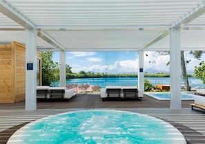 Un espace avec un bain à remous offrant une vue sur un lac et des montagnes.