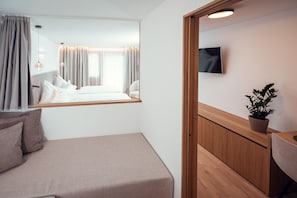 A hotel room with a bed, a small desk, a potted plant, and a TV on the wall. - Ganischgerhof - Mountain Resort & Spa (Nova Ponente)