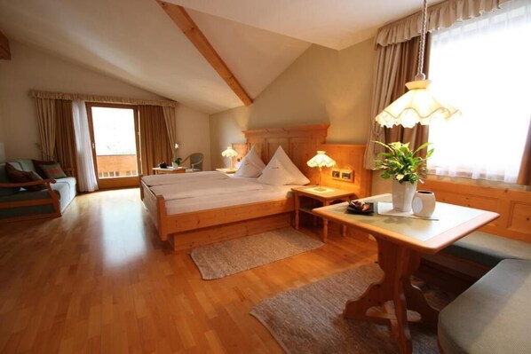 Ein gemütliches Schlafzimmer mit einem hölzernen Bett, einem Schreibtisch, einem Stuhl und einem Fenster mit Vorhängen.