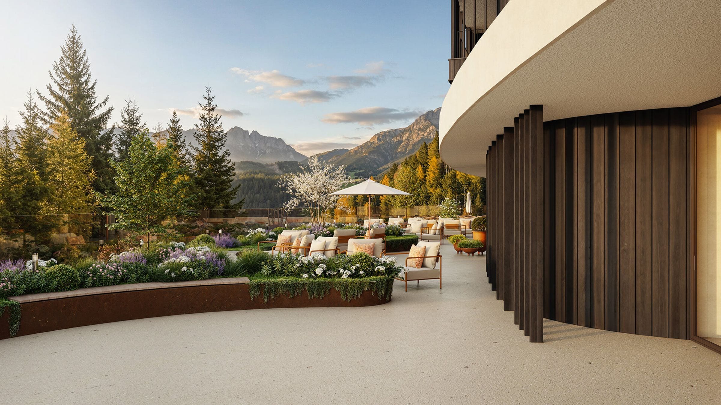An outdoor seating area with a view of mountains, surrounded by greenery and a modern building facade.