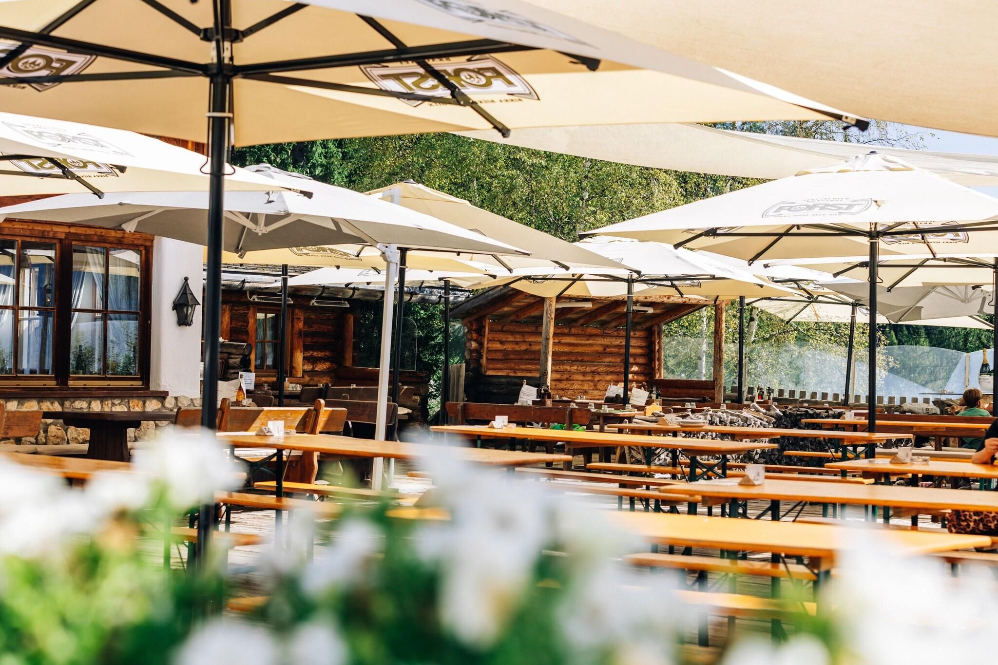 An outdoor dining area with wooden tables and white umbrellas.