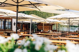 An outdoor dining area with wooden tables and white umbrellas.