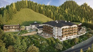 Een meerlaags hotel met een zwembad, omgeven door weelderige begroeiing en een bebost heuvel.