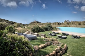 A landscaped outdoor area with a swimming pool, lounge chairs, and a hill in the background. - Veridia Resort, a Member of Radisson Individuals (Domus de Maria)