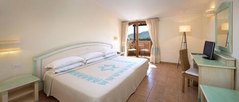 Une chambre d’hôtel avec un lit, un bureau équipé d’un ordinateur, une chaise et un balcon avec vue.